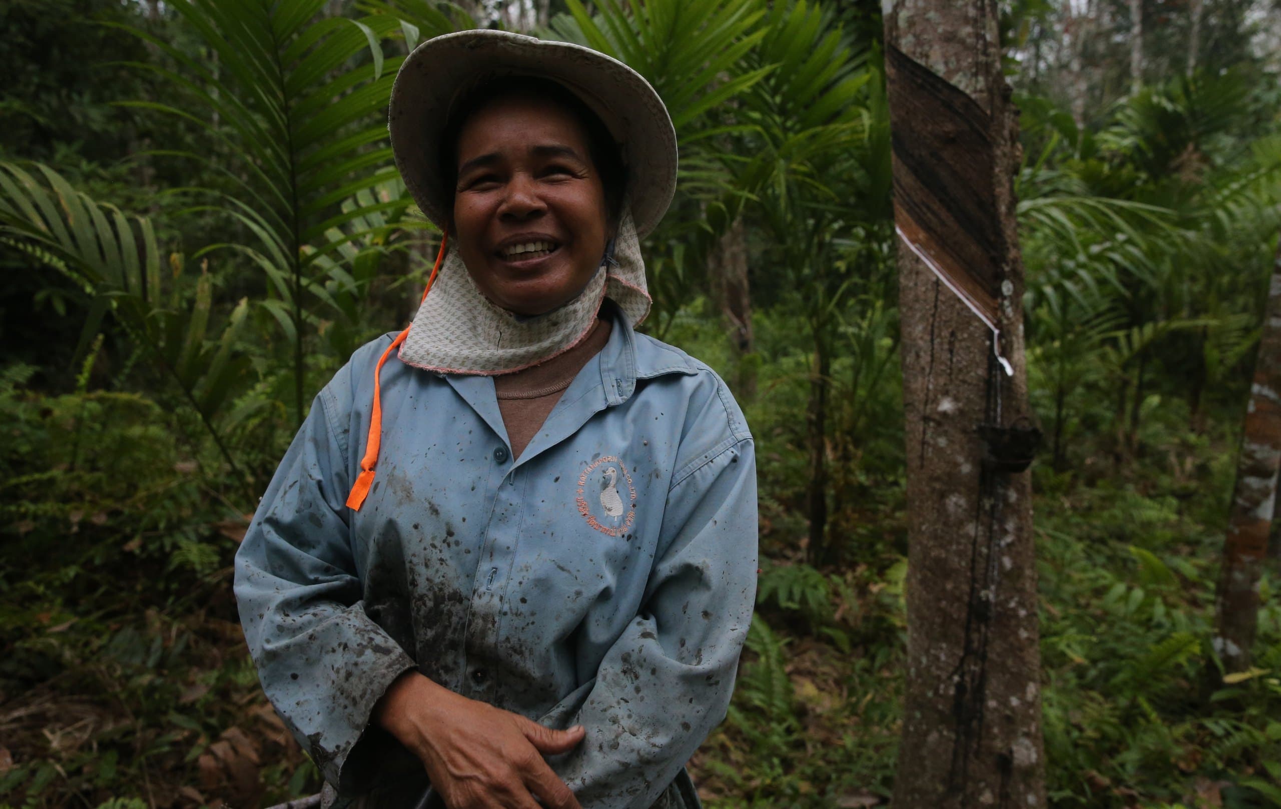 Chorthip Prabpree, a rubber tapper, smiling in her Wanakaset forest garden beside a latex collection sheet
